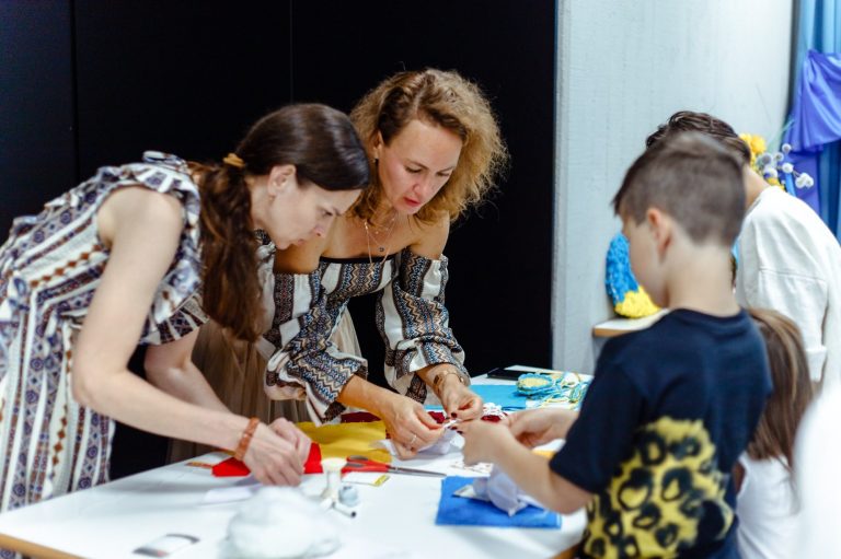 Zur Seite Bildungsangebote Zwei Frauen und ein Junge basteln gemeinsam an einem Tisch.